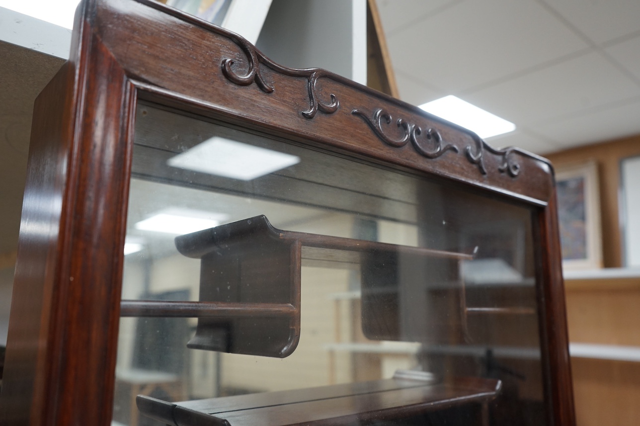 A narrow Chinese hardwood display cabinet, fitted with decorative shaped hardwood shelving, 82.5cm high x 53cm wide at base x 10.5cm deep at base. Condition - marks to wood when cello tape has been, other wise good